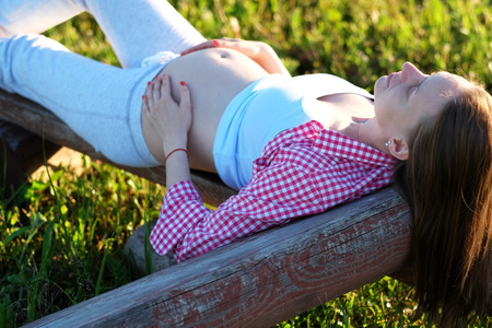 Pregnant woman outdoors at sunny summer dayの写真素材