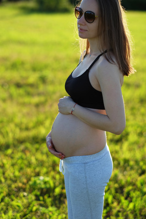 Pregnant woman outdoors at sunny summer dayの写真素材