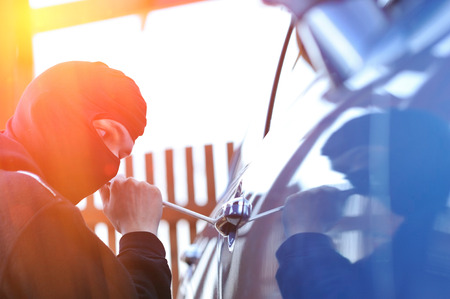 Young man in mask trying to steal a carの写真素材