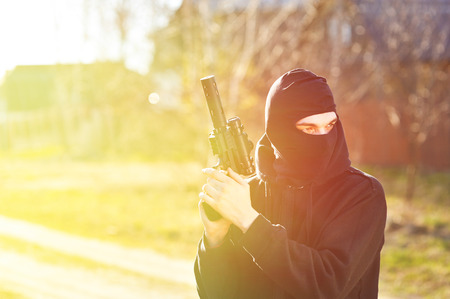 Gunman in black mask holding gun with silencerの写真素材