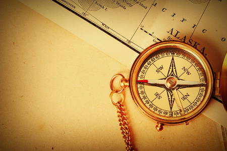 Antique brass compass over old Alaska map