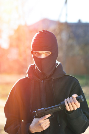 Gunman in black mask holding gun with silencerの写真素材