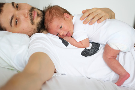 Three weeks old newborn with his father. Shallow depth of field.