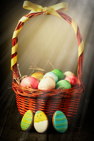 Colored easter eggs in basket on wooden tableの写真素材