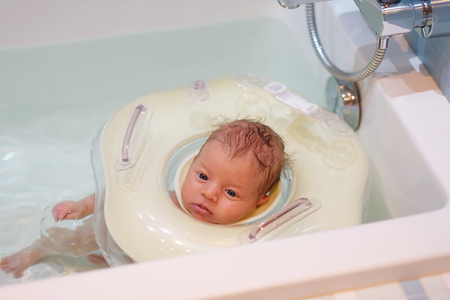 Newborn baby swimming with neck swim ringの写真素材