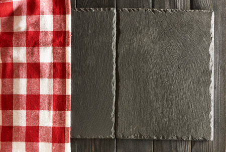 Empty slate plates and tablecloth over black wooden background