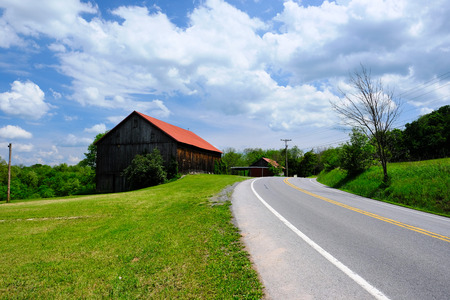 Old red roof barn near highway in Pennsylvania at sunny summer dayの写真素材