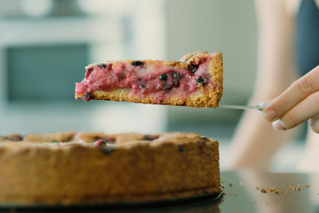 Woman holding wild berry homemade pie slice with raspberries and blueberries. Shallow depth of field.の写真素材