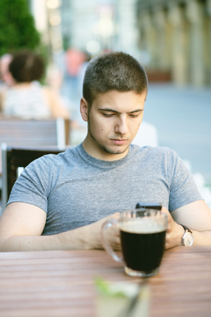 Young man with mobile phone in outdoor restaurantの写真素材