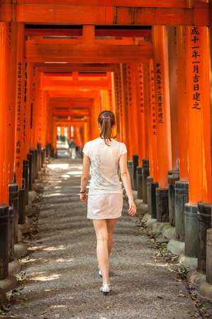 Woman walking through wooden Torii Gates at Fushimi Inari Shrine, Kyoto, Japanのeditorial素材