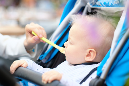 Baby boy with blue eyes sitting in modern stroller