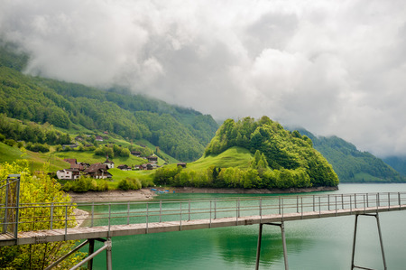 Beautiful emerald mountain lake Lungern in Switzerland under low cloudsの写真素材
