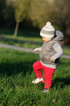 Portrait of toddler child in warm vest jacket outdoors. One year old baby boy wearing vest jacket at...