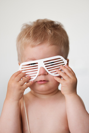 Baby boy with paper glasses on a stickの写真素材
