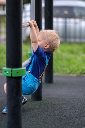 Portrait of toddler child outdoors wearing shorts and suspenders. One year old baby boy at playgroundの写真素材