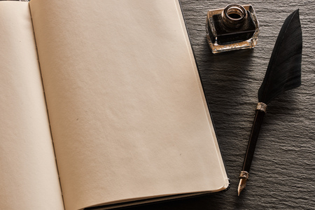 Feather pen and blank notebook page over slate backgroundの写真素材