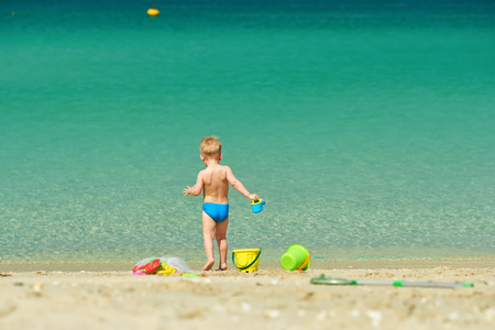 Two year old toddler boy playing with beach toys on beach の写真素材