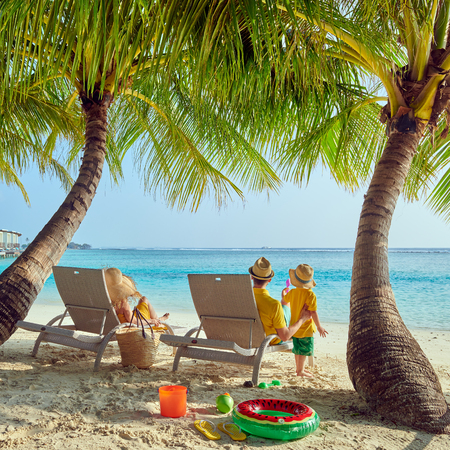 Family on beach, young couple in yellow with three year old boy. Summer vacation at Maldives.の写真素材