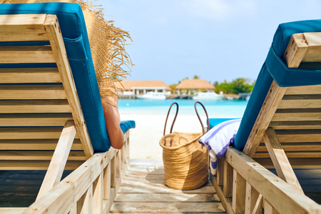 Young woman at beach on wooden sun bed loungers. Summer vacation at Maldives.の写真素材