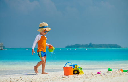 Three year old toddler boy playing with beach toys on beach. Summer family vacation at Maldives.の写真素材