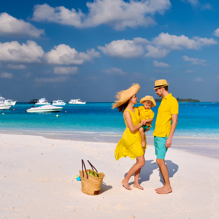 Family on beach, young couple in yellow with three year old boy. Summer vacation at Maldives.の写真素材
