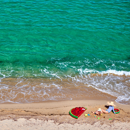 Two year old toddler boy and his mother on beach with inflatable float and ring. Summer family vacation. Sithonia, Greece.の写真素材