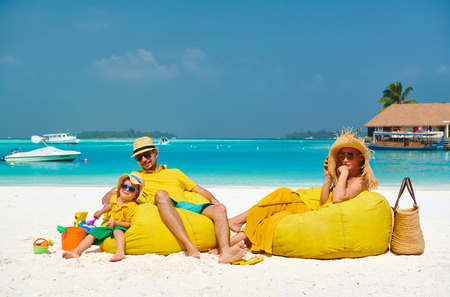 Family on beach, young couple in yellow with three year old boy. Summer vacation at Maldives.の写真素材