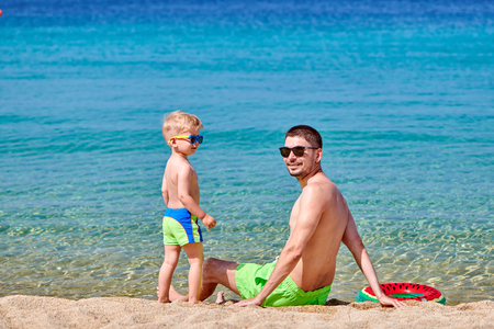 Two year old toddler boy on beach with fatherの写真素材