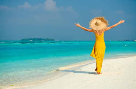 Woman in dress walking on tropical beach with arms outstretched. Summer vacation at Maldives.の写真素材