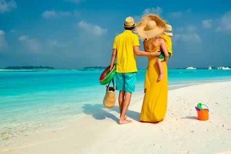 Family on beach, young couple in yellow with three year old boy. Summer vacation at Maldives.の写真素材