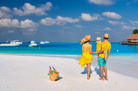 Family on beach, young couple in yellow with three year old boy. Summer vacation at Maldives.の写真素材