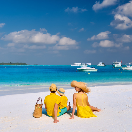 Family on beach, young couple in yellow with three year old boy. Summer vacation at Maldives.の写真素材