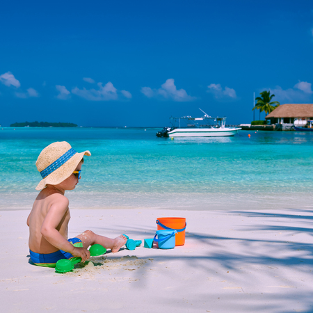 Three year old toddler boy playing with beach toys on beach.  Summer family vacation at Maldives.の写真素材