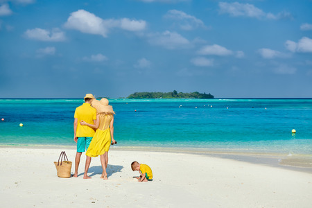 Family on beach, young couple in yellow with three year old boy. Summer vacation at Maldives.の写真素材