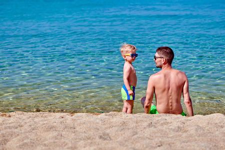 Two year old toddler boy on beach with fatherの写真素材