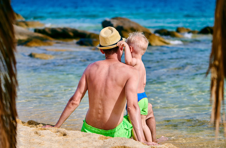 Two year old toddler boy on beach with fatherの写真素材