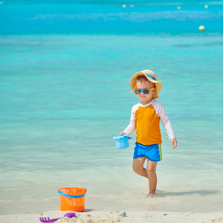 Three year old toddler boy playing with beach toys on beach. Summer family vacation at Maldives.の写真素材