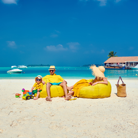 Family on beach, young couple in yellow with three year old boy. Summer vacation at Maldives.の写真素材