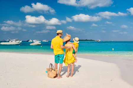 Family on beach, young couple in yellow with three year old boy. Summer vacation at Maldives.の写真素材