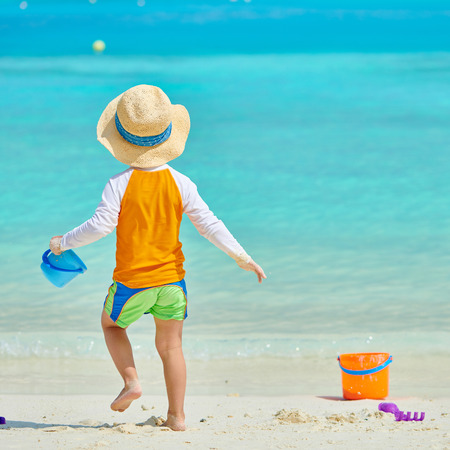 Three year old toddler boy playing with beach toys on beach. Summer family vacation at Maldives.の写真素材
