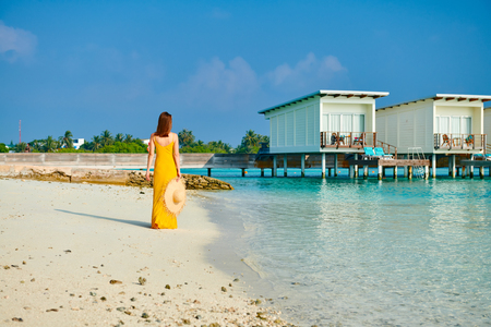 Woman in dress walking on tropical beach. Summer vacation at Maldives.の写真素材