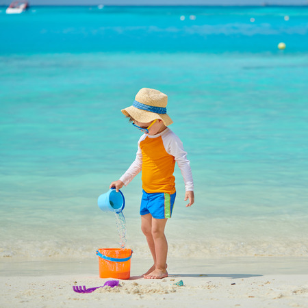 Three year old toddler boy playing with beach toys on beach. Summer family vacation at Maldives.の写真素材