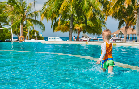 Three year old toddler boy in resort swimming pool. Summer family vacation at Maldives.の写真素材