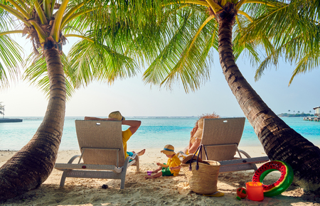 Family on beach, young couple in yellow with three year old boy. Summer vacation at Maldives.の写真素材