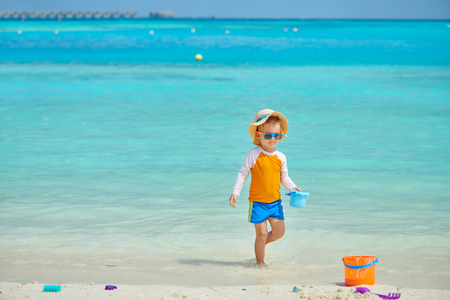 Three year old toddler boy playing with beach toys on beach. Summer family vacation at Maldives.の写真素材