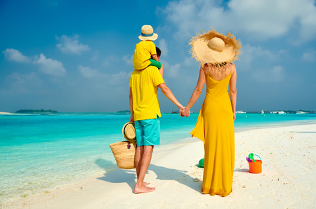Family on beach, young couple in yellow with three year old boy. Summer vacation at Maldives.の写真素材