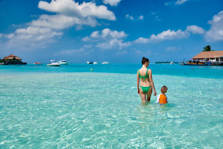 Three year old toddler boy on beach with mother having fun in shallow water. Summer family vacation at Maldives.の写真素材