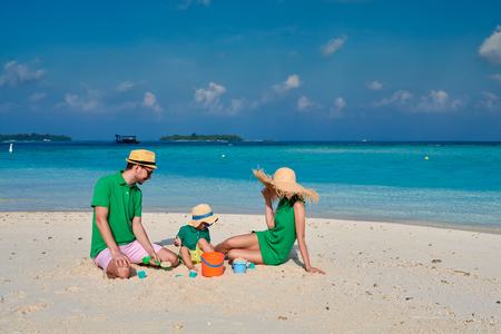 Family on beach, young couple in green with three year old boy. Summer vacation at Maldives.の写真素材