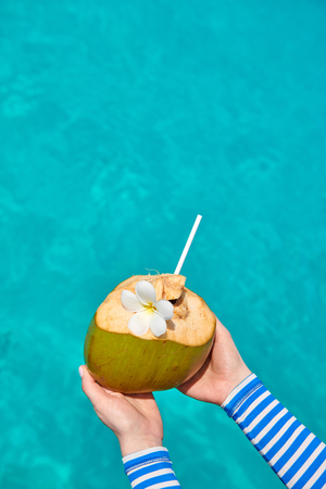 Coconut in hands over against turquoise sea. Summer vacation at Maldives.の写真素材