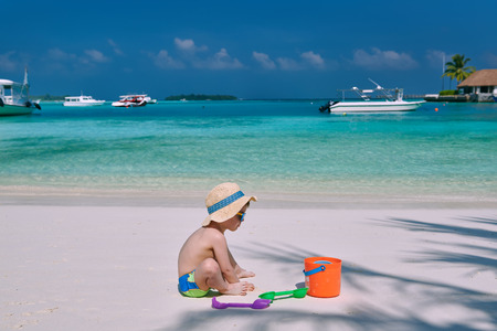 Three year old toddler boy playing with beach toys on beach.  Summer family vacation at Maldives.の写真素材